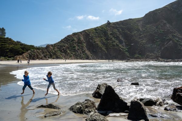 Children run away from the waves at Pfeiffer Beach in Big Sur, CA