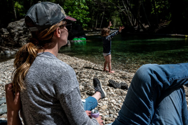 A mom watches her son throw rocks in the river at Pfeiffer State park in Big Sur, CA