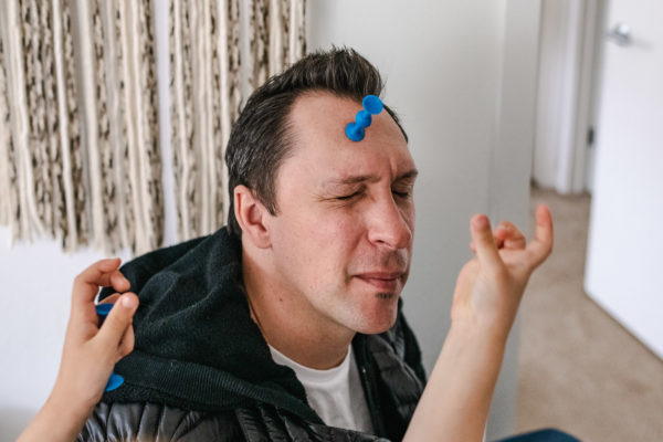 A dad closes his eyes while his daughter sticks things on his forehead in Berkeley, CA