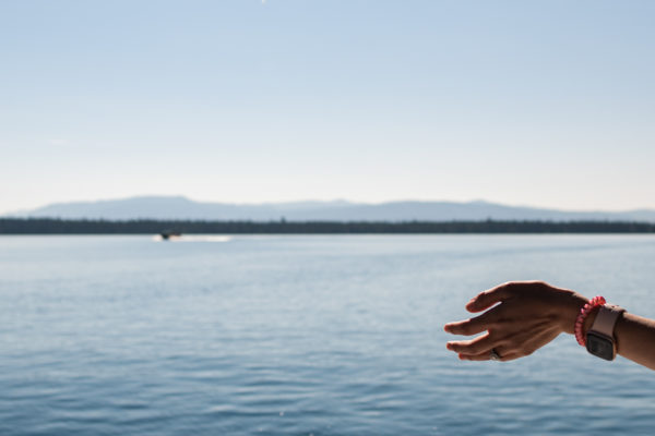 A woman holds her hand out to experience the fresh air while boating across the lake in the Grand Tetons, WY