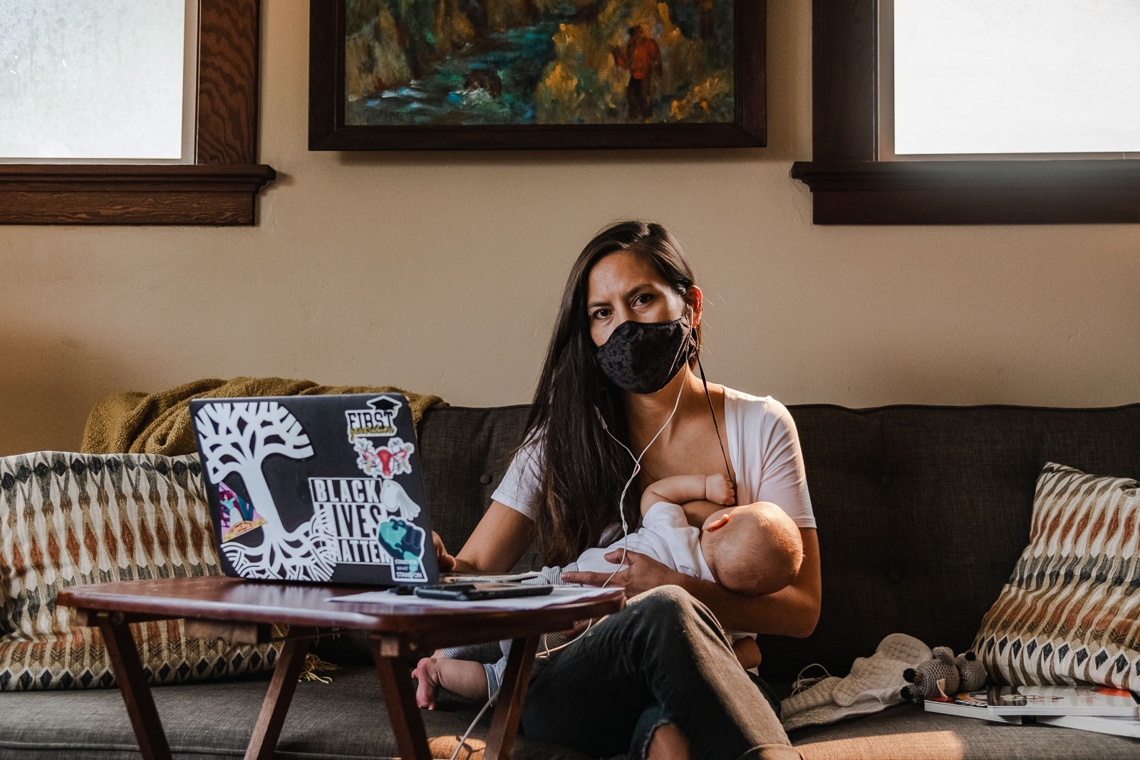 A mother breastfeeds her newborn baby while working at home in Oakland, CA