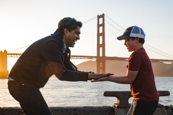 A man and young boy play slaps in front of the Golden Gate Bridge in San Francisco, CA