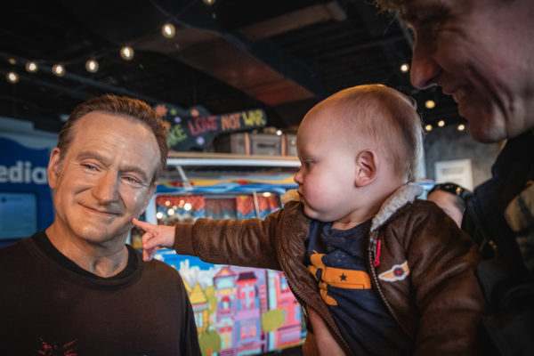 A child touches a wax figure of Robin Williams in San Francisco, CA