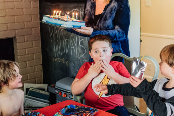 A young boy looks surprised as his mom brings out his birthday cake in Oakland, CA