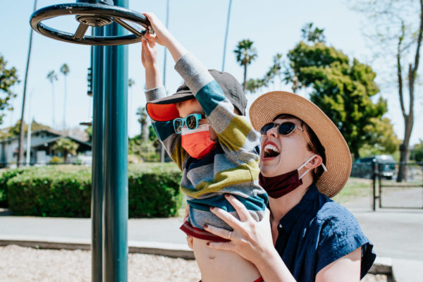 A mom laughs with her boy on playground equipment in Washington Park, Alameda, CA