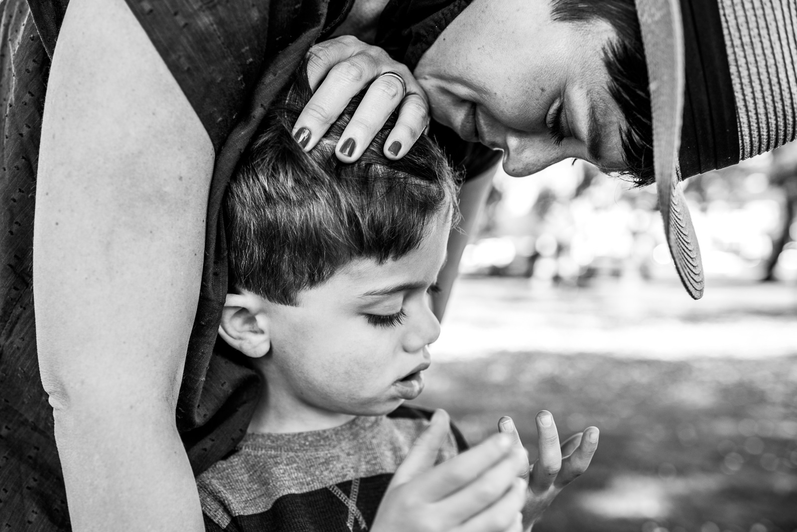 A mom comforts her son while he looks at his hand at Washington Square Park in Alameda, CA