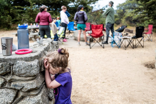 A young girl plays hide n seek while camping at Sunset State Beach in Santa Cruz, CA