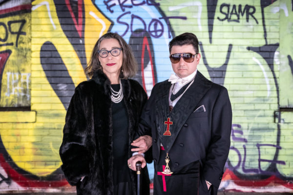 A mother and son stand together in front of a graffiti wall in Oakland, CA during a photo shoot.