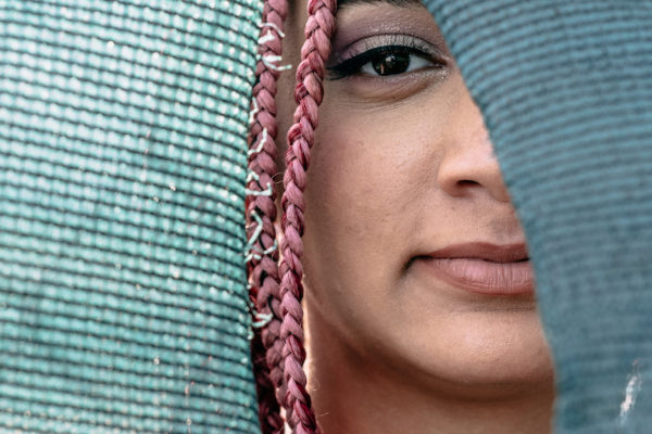 Teen girl peers through a hole in a screen during a senior photography session in Alameda, CA