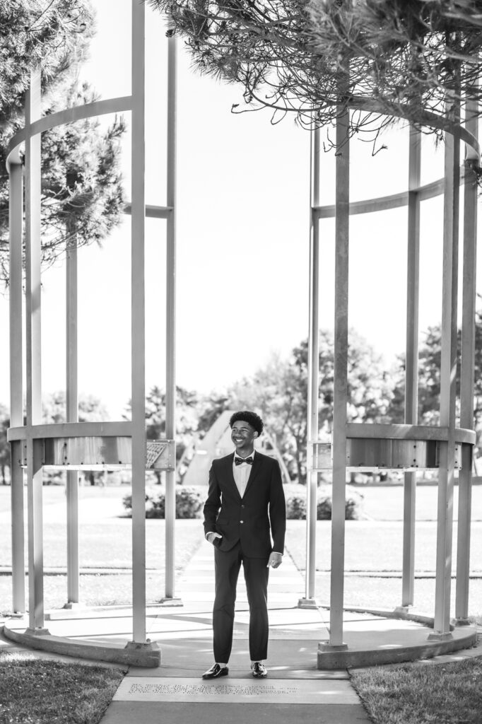 A black and white photo of a young man wearing a tuxedo standing outside for a senior photo shoot in the San Francisco Bay Area