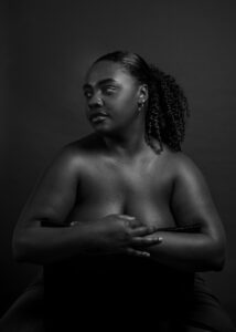 One black woman sits in a chair backwards while posing for a boudoir photo shoot in Emeryville, CA