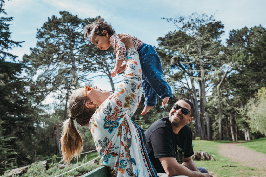 Family enjoying a sunny picnic at a San Francisco park with their white dog front and center, showcasing relaxed weekend vibes