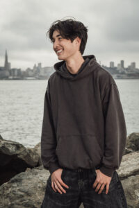 High School Senior wearing a brown hoodie poses for a Senior picture in San Francisco