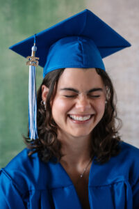 Senior Grad in a blue cap and gown laughing in an Alameda Photography studio